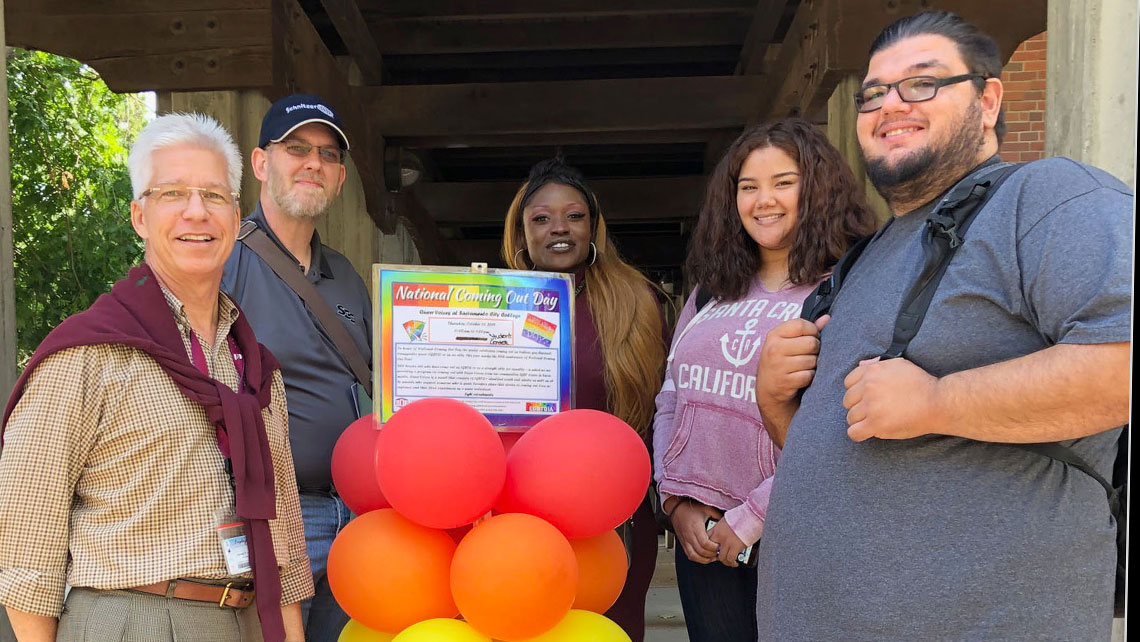 National Coming Out Day group photo with rainbow balloons
